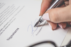 a close up of someone signing a contract